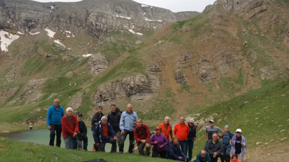 El grupo, frente al ibón y el paisaje montañoso al fondo.