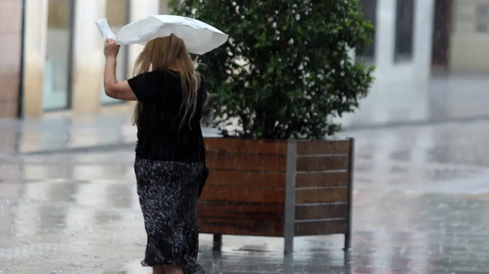 Una señora se resguarda de la lluvia con una bolsa de plástico.