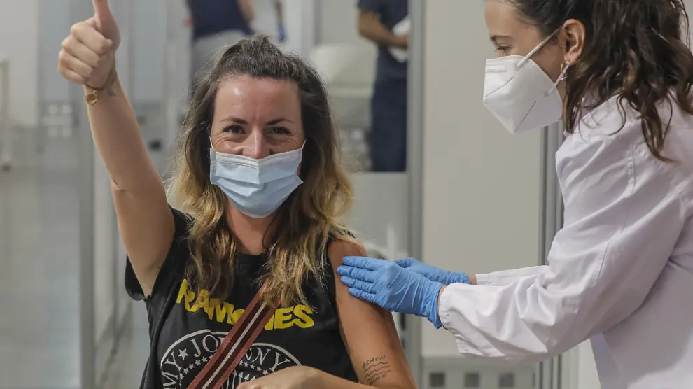 Una joven sonríe y saluda mientras recibe la vacuna contra la Covid-19 en la Ciutat de les Arts i les Ciències de Valencia