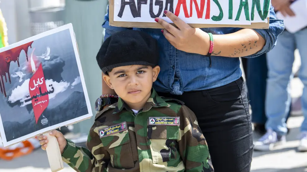 Un niño muestra una pequeña pancarta en apoyo a Afganistán.