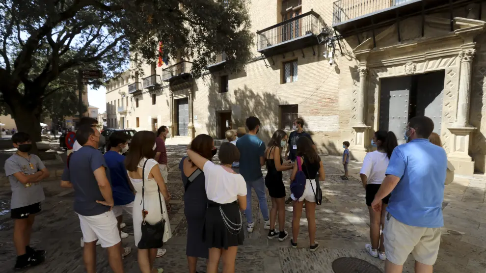 Grupo de turistas atendiendo a las explicaciones del guía en la plaza de la Catedral de Huesca.