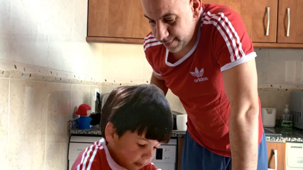 Lorenzo mayor contempla al Lorenzo niño -ambos con la misma camiseta- trabajando en la mesa de la cocina en un montaje que hizo al cumplir 40 años.
