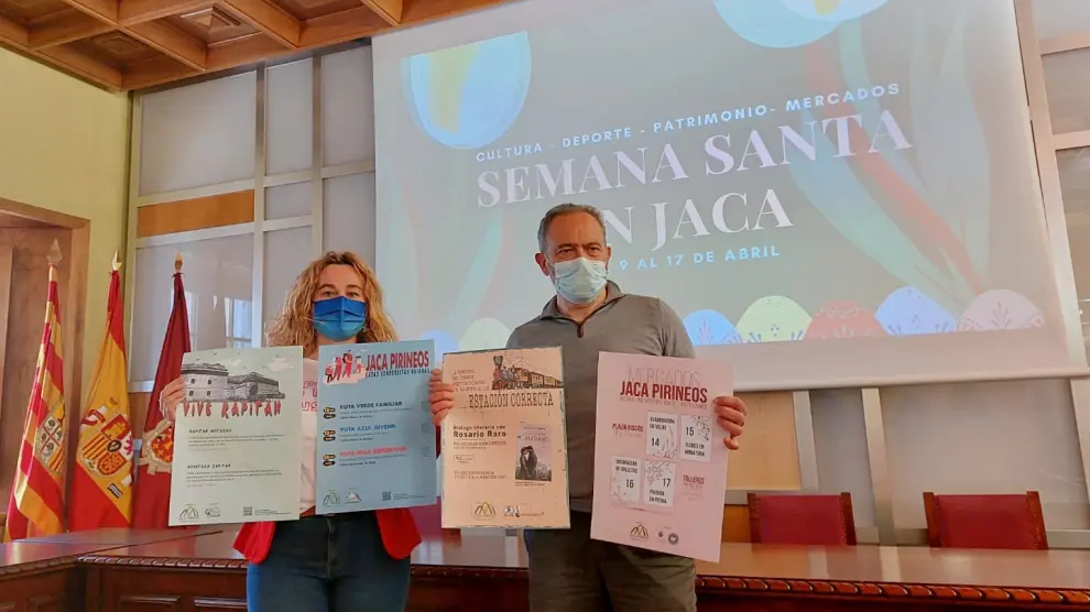 Olvido Moratinos y Javier Acín muestran los carteles de las actividades en el Salón de Ciento del Ayuntamiento de Jaca.