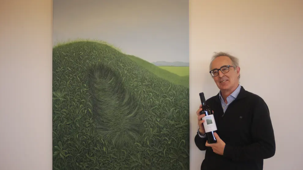 Jorge Fin posa con una botella de la Bodega Enate con la obra ganadora de la beca en la etiqueta.