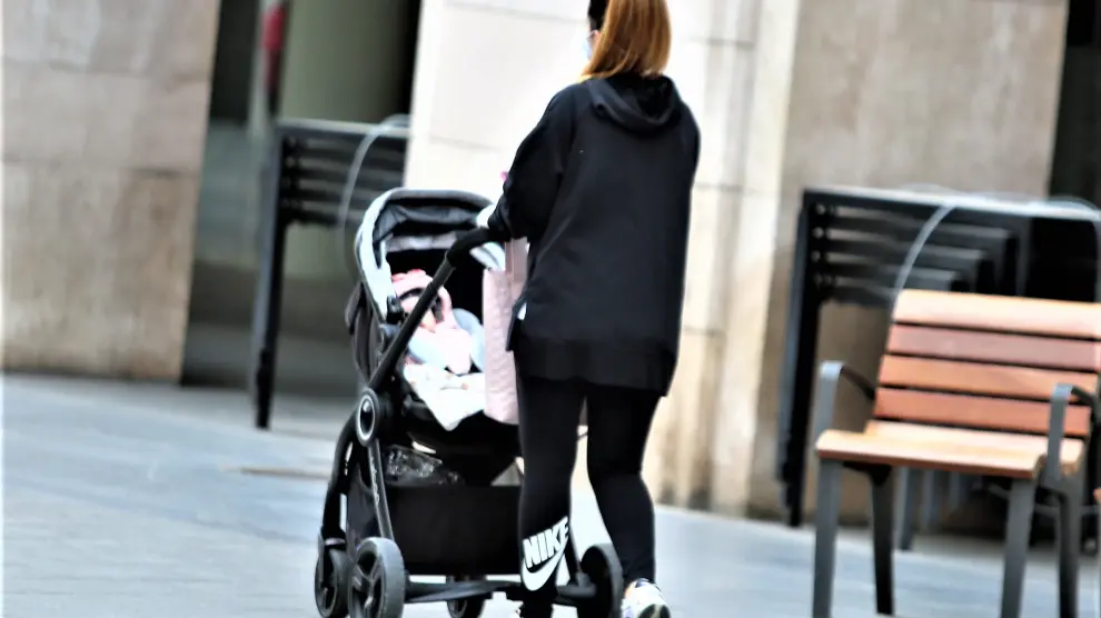 Foto de archivo de una joven paseando un bebé por el centro de Huesca.
