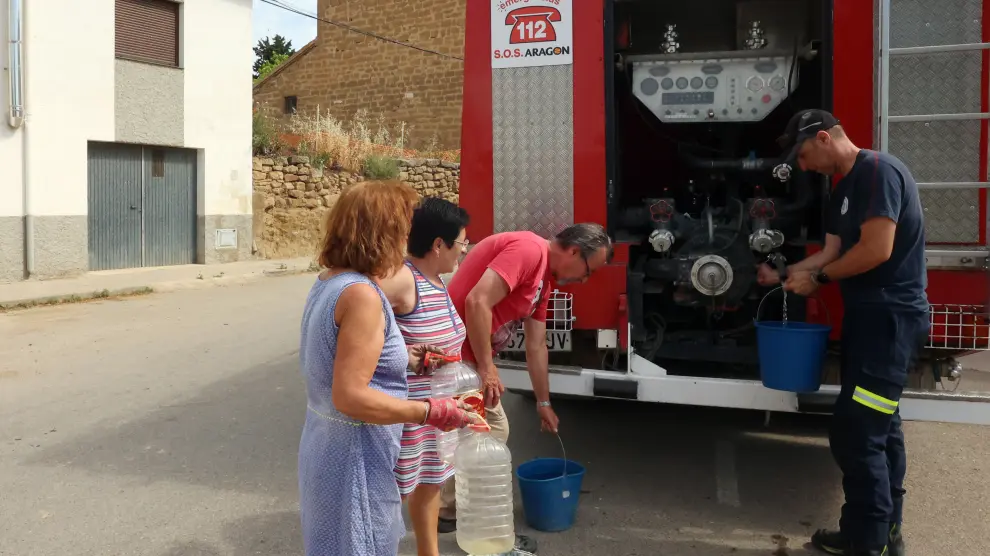 Vecinos de Liesa recogen agua del camión de bomberos en la mañana de este jueves.