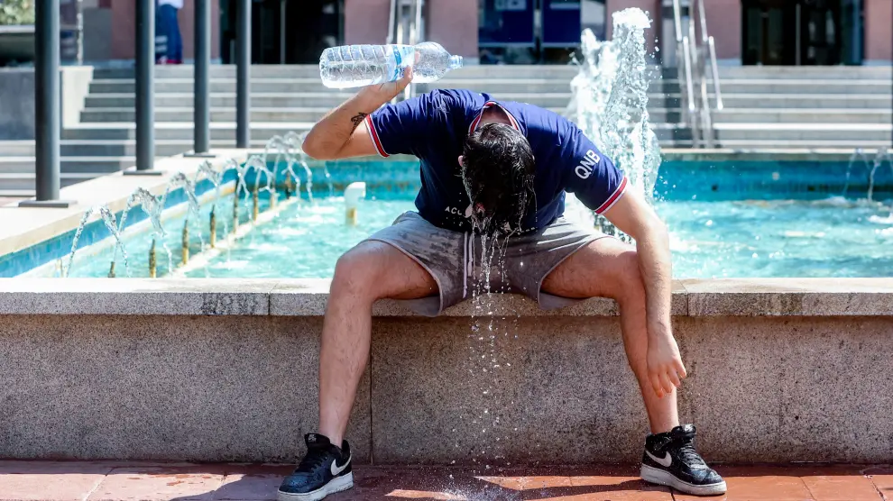 Un joven se tira una botella de agua por encima para combatir la segunda ola de calor del verano. F