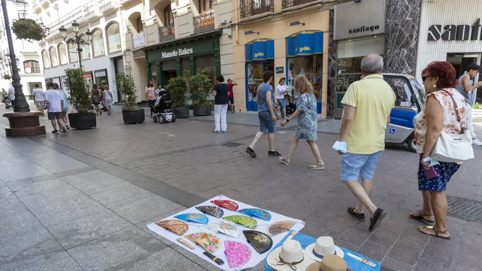 Sombreros y abanicos a la venta en un puesto ambulante en una calle de Zaragoza.