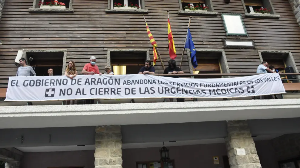 Vecinos de la zona colocando la pancarta contra el cierre de las urgencias médicas en el balcón del Ayuntamiento de Canfranc.