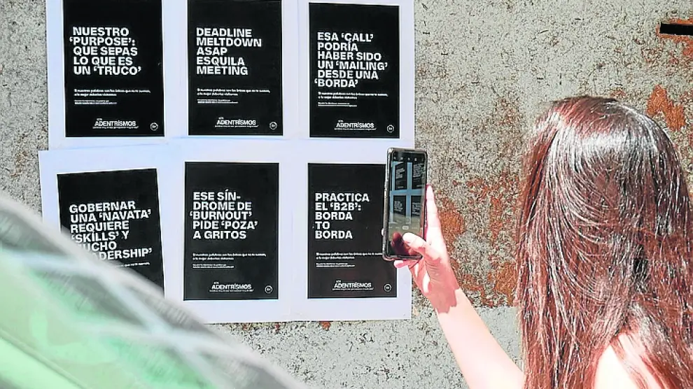 Una mujer realiza una foto con su móvil a los carteles de la campaña colgados en una zona empresarial de Madrid.