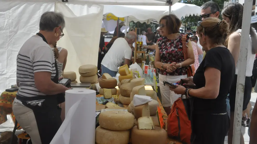 Varios asistentes se interesan por los quesos expuestos en uno de los puestos de la feria.