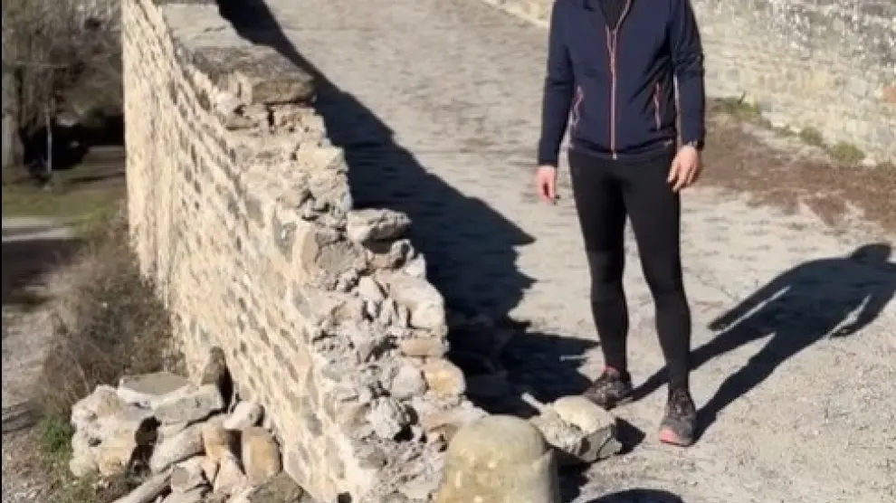 El alcalde de Jaca, Carlos Serrano, muestra las piedras derribadas en uno de los extremos del muro del puente San Miguel.