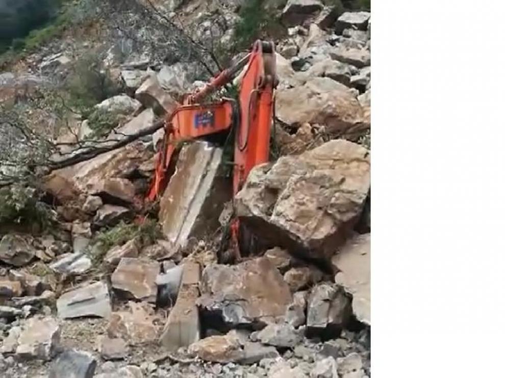Imagen de la excavadora prácticamente sepultada bajo la avalancha de piedras.