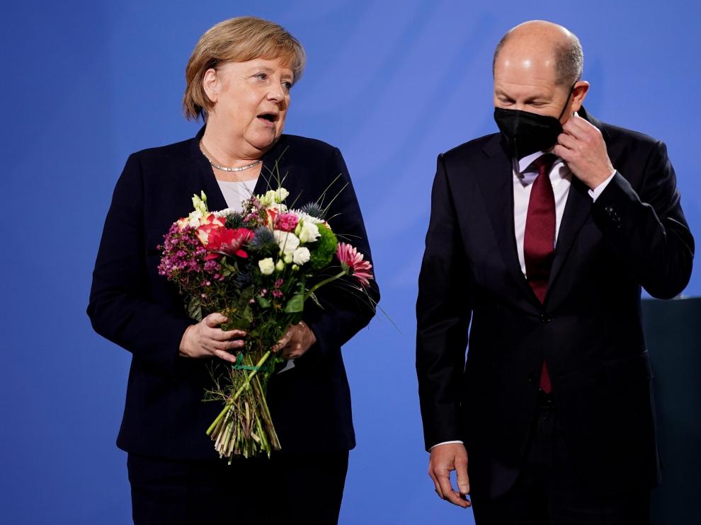 Merkel, con un ramo de flores, junto a su relevo, Olaf Scholz.