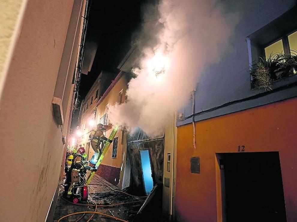 Los bomberos rescatan a una mujer de una casa incendiada en la calle Sobrarbe