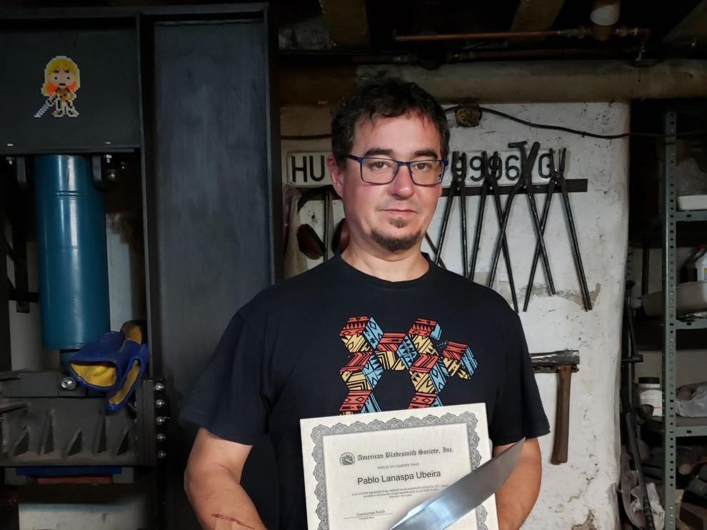 Pablo, en su taller de Berdún, muestra el diploma y uno de sus cuchillos.