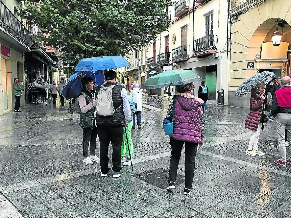 Ciudadanos ayer con sus paraguas en el Coso.