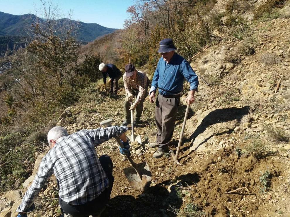 Vecinos de Yebra limpian un derrumbe de tierra en el camino de Santa Orosia