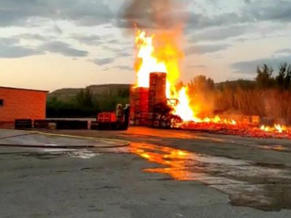 El fuego quema los "palots" apilados en el exterior de un almacén de fruta en Fraga