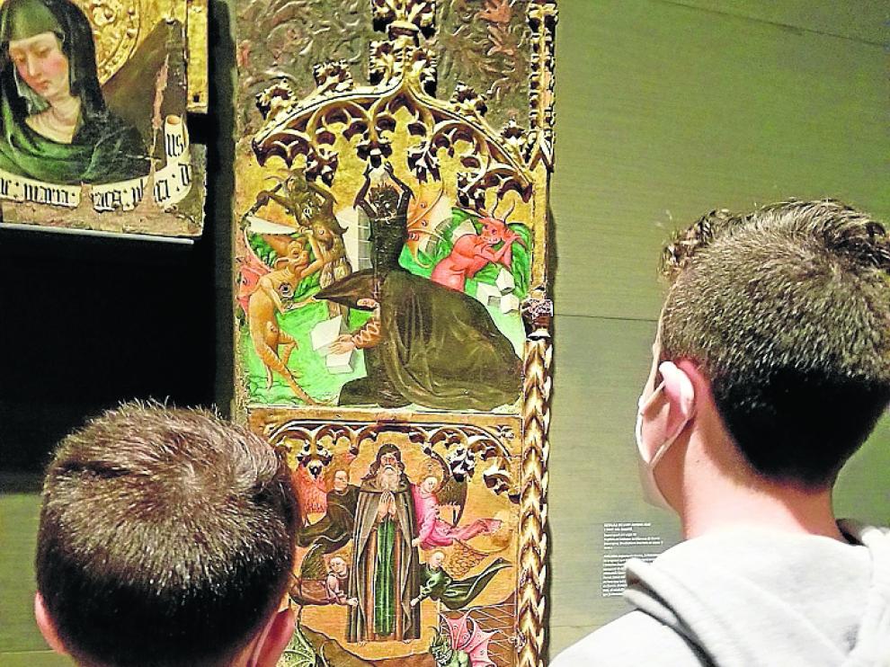 Dos niños miran el Retablo de San Antonio Abad de Monzón, expuesto en el Museo de Lérida.