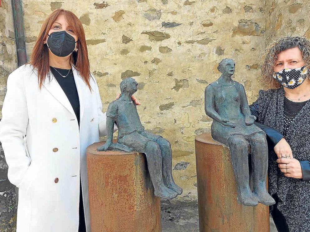 La alcaldesa de Sabiñánigo, Berta Fernández, y la concejala Marisa Morillo, junto a la escultura homenaje a la maestra rural.
