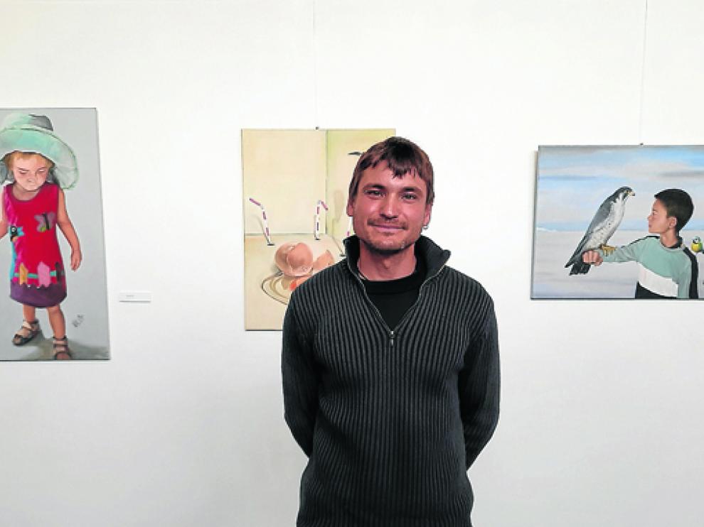 Javier Valero junto a tres de las obras que conforman la exposición Efluvios gráficos.
