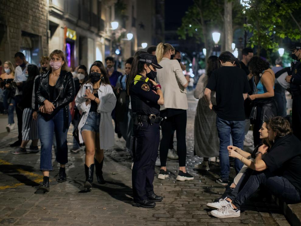 Una agente de policía pide a una pareja que se ponga la mascarilla, en la zona del Born de Barcelona, durante la noche del sábado.