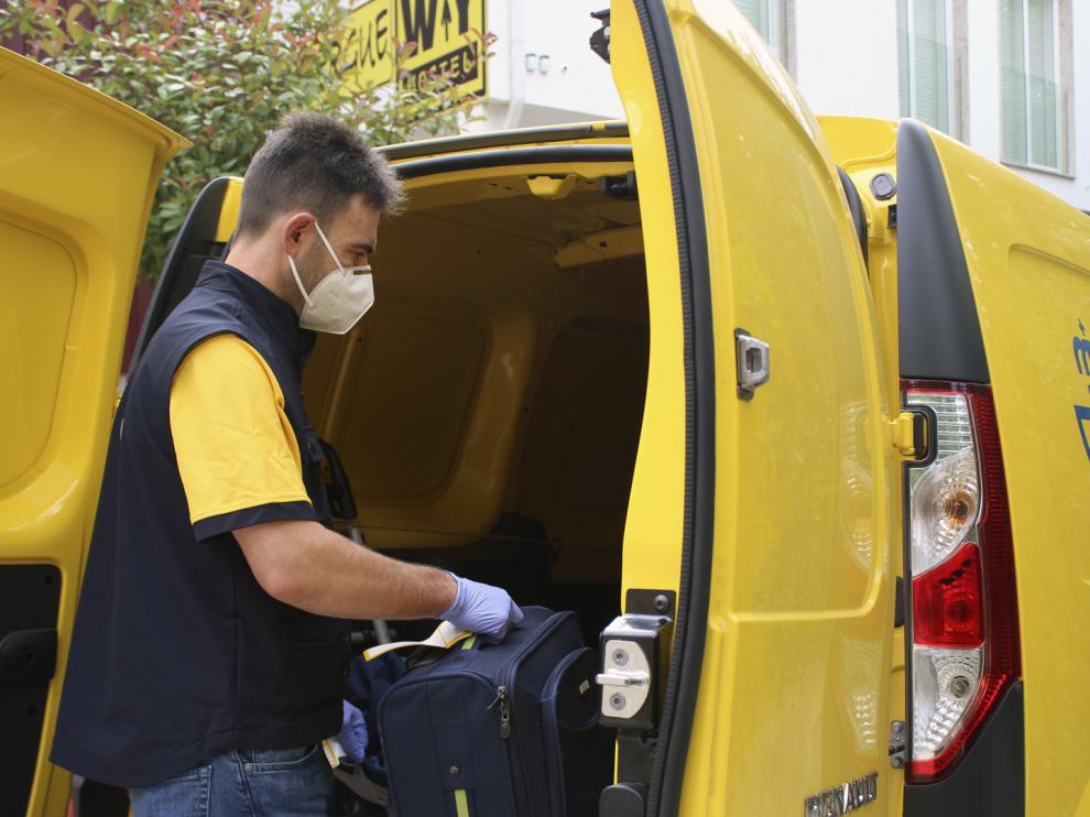 Un trabajador de la empresa de Correos introduce una maleta en una furgoneta de reparto.