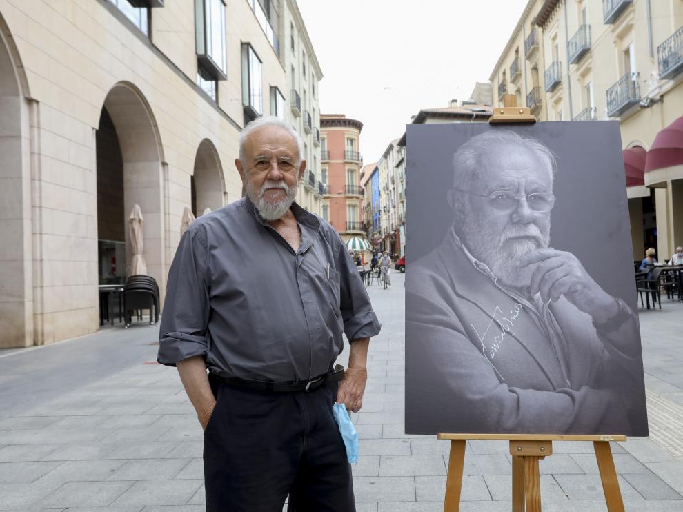 Gonzalo Suárez, posando con su retrato en los Porches de Galicia.