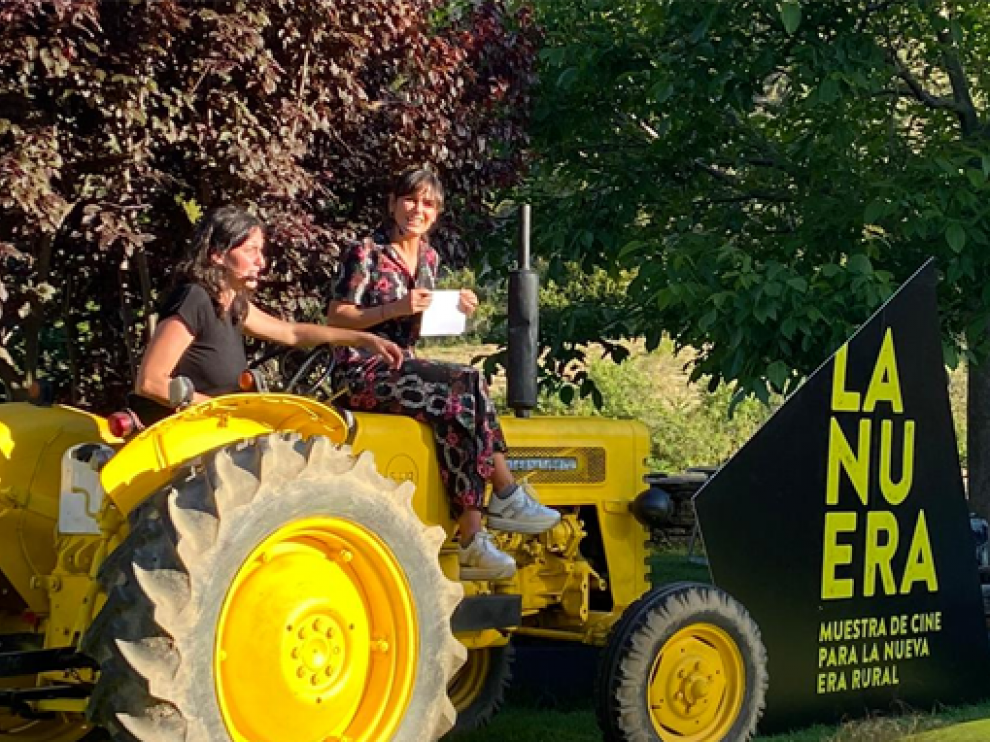 Elena S. Sánchez (derecha), subida al tractor que aparecía en el cartel, durante su inauguración.