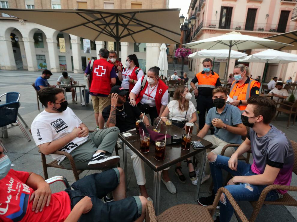 Jóvenes voluntarios conciencian a la población oscense de la covid con el reparto de estas protecciones.