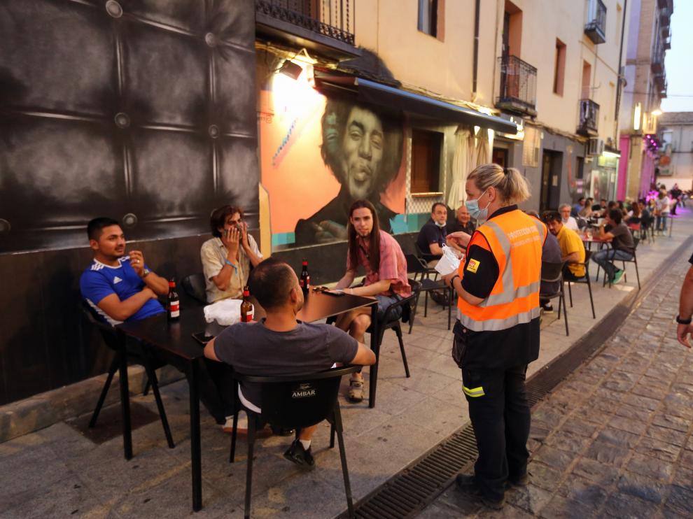 Jóvenes voluntarios conciencian a la población oscense de la covid con el reparto de estas protecciones.