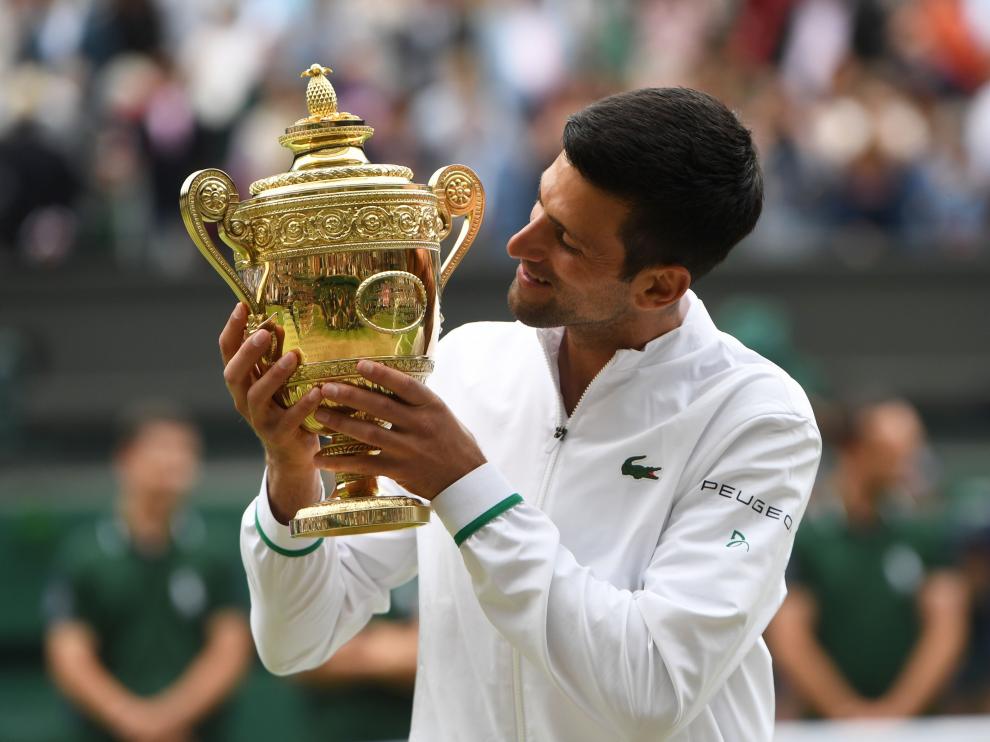 Djokovic mira al trofeo de campeón en la pista central de Wimbledon.