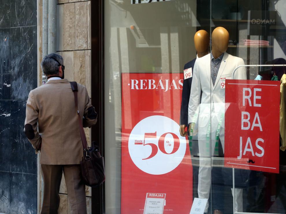Un consumidor mira un escaparate de una tienda de ropa de caballero de la capital oscense.