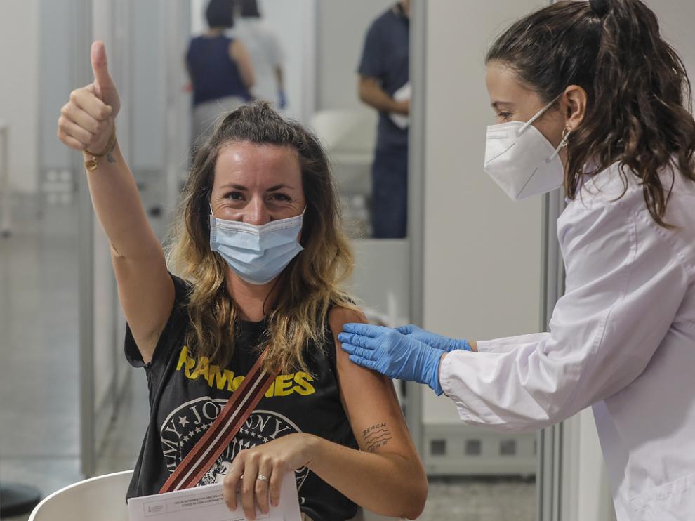 Una joven sonríe y saluda mientras recibe la vacuna contra la Covid-19 en la Ciutat de les Arts i les Ciències de Valencia
