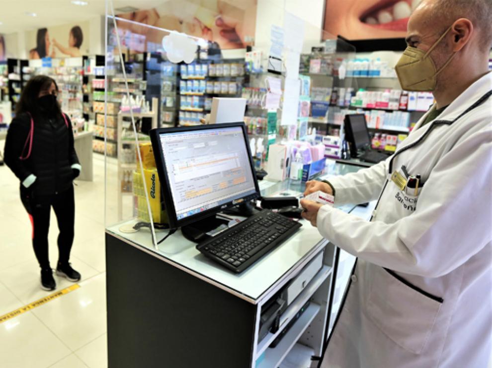 Un profesional de la farmacia Barreña, situada en la ciudad de Huesca, atiende a una clienta.
