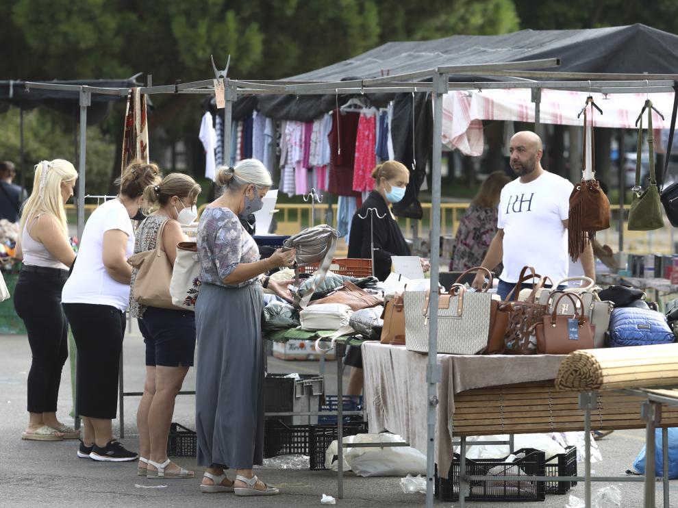 Clientas observan bolsos en un puesto ambulante del mercadillo de Huesca.