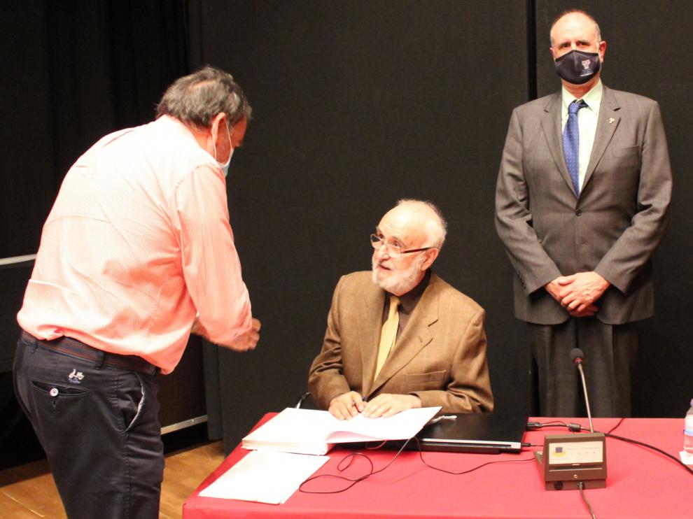 Isidro Bango Torviso (en el centro) firma un ejemplar de su libro, en el Palacio de Congresos de Jaca, en presencia de Juan Carlos Moreno, presidente de la Asociación Sancho Ramírez.