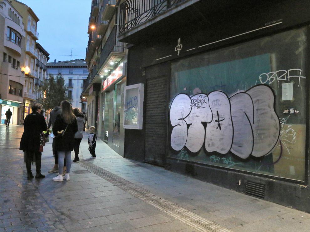 Un local comercial del Coso Bajo sin actividad con una gran pintada en su escaparate, este viernes por la tarde.