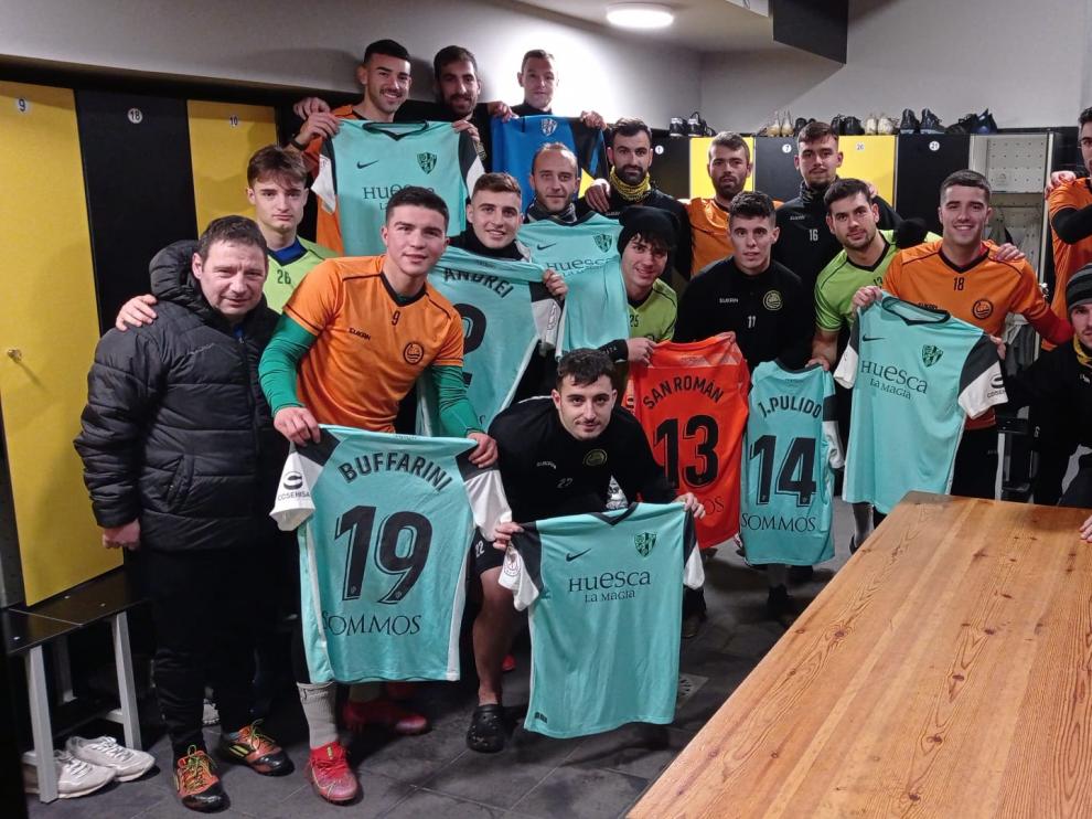 Jugadores y cuerpo técnico del Cayón, en el vestuario con camisetas del Huesca.