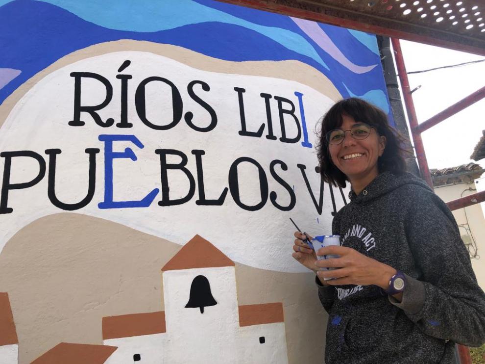 Rosa Mai pintando el deposito de agua de la localidad de Erés.