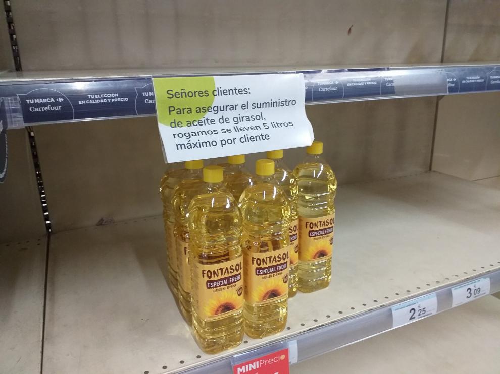 Un cartel, en un estante casi vacío, limita la compra de aceite de girasol en un supermercado.
