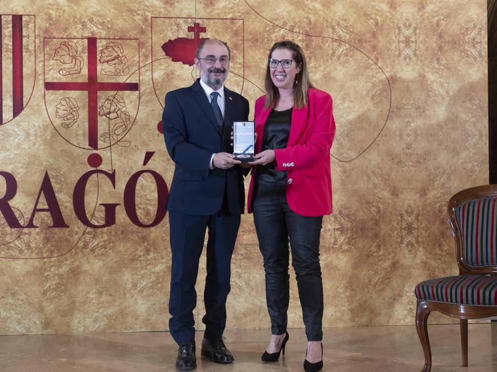 El presidente del Gobierno de Aragón, Javier Lamban, hace entrega de la "Medalla Aragonesa de la Educación" a la directora del colegio de educación especial Gloria Fuertes de Andorra, Lola Oriol, en el acto Institucional del Día de San Jorge en Teruel.