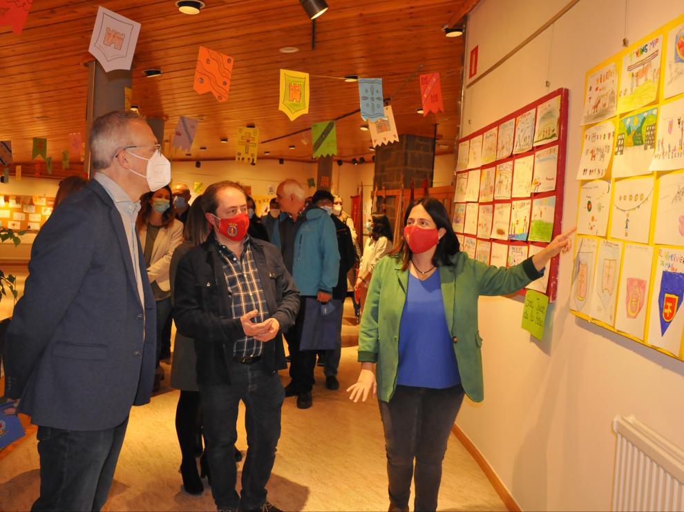Cristina Martínez explica el contenido de la exposición al presidente de la hermandad y al alcalde de Jaca.
