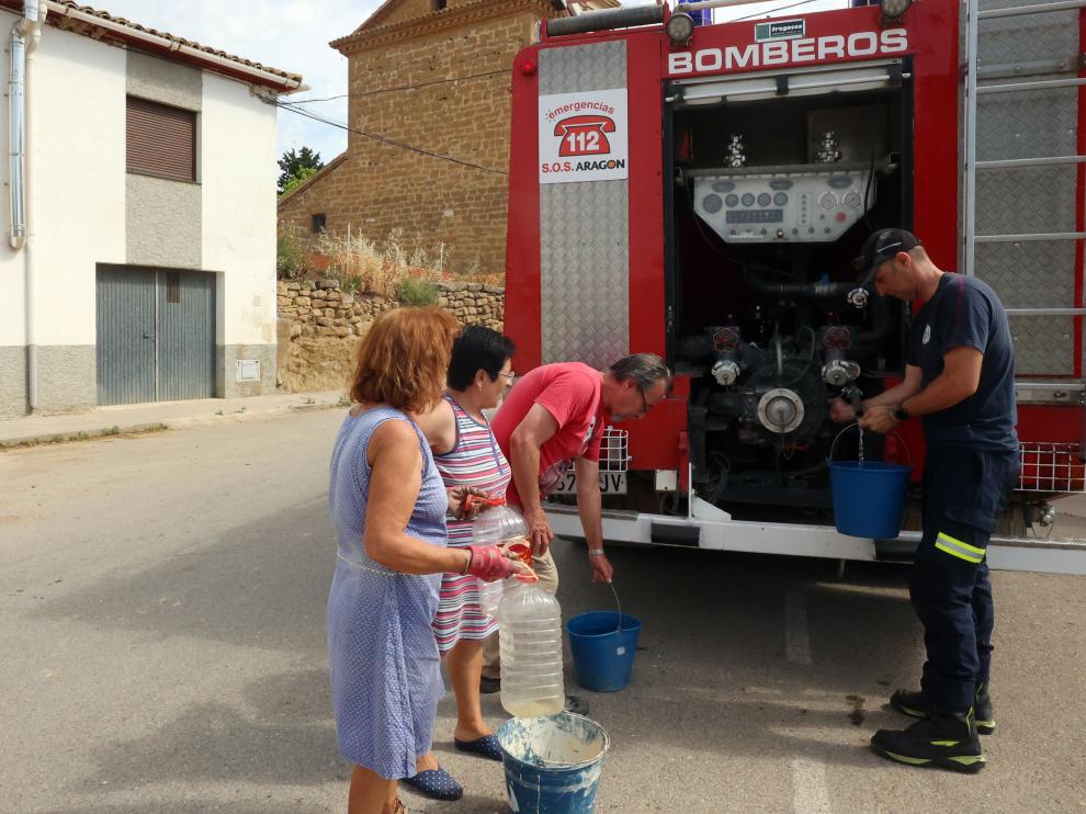 Vecinos de Liesa recogen agua del camión de bomberos en la mañana de este jueves.
