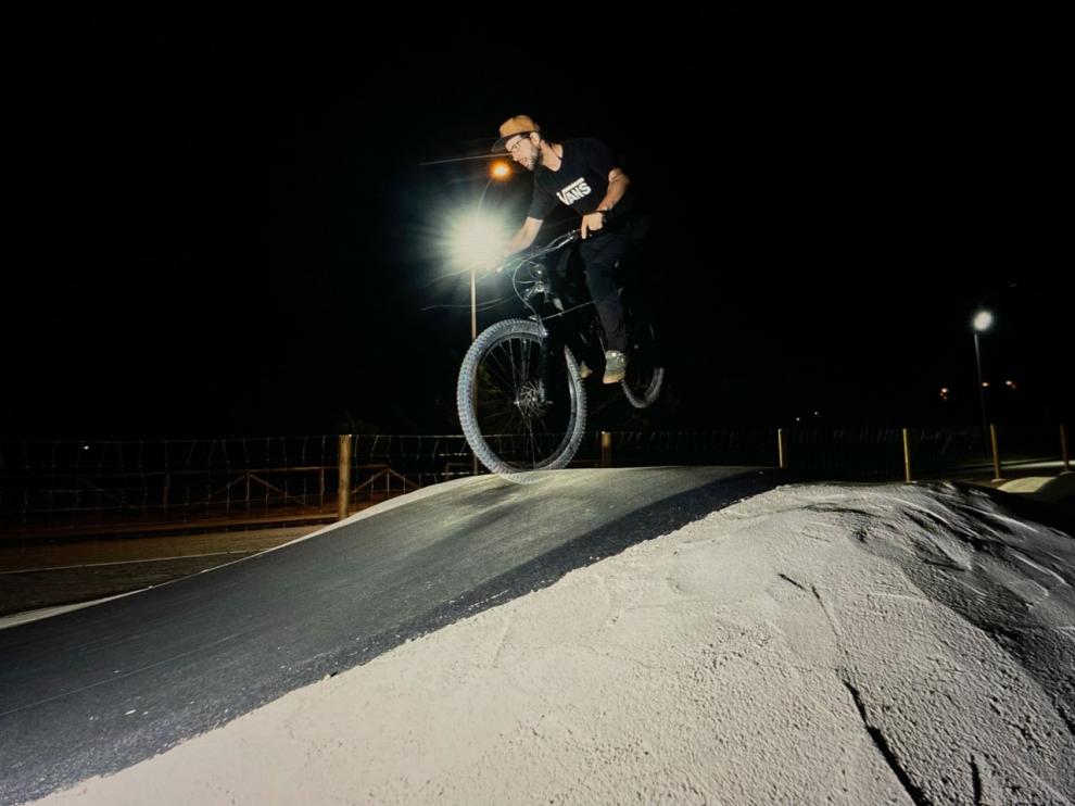 Biker realiza trucos en las instalaciones del Pump Truck de Villanúa iluminado durante la noche.