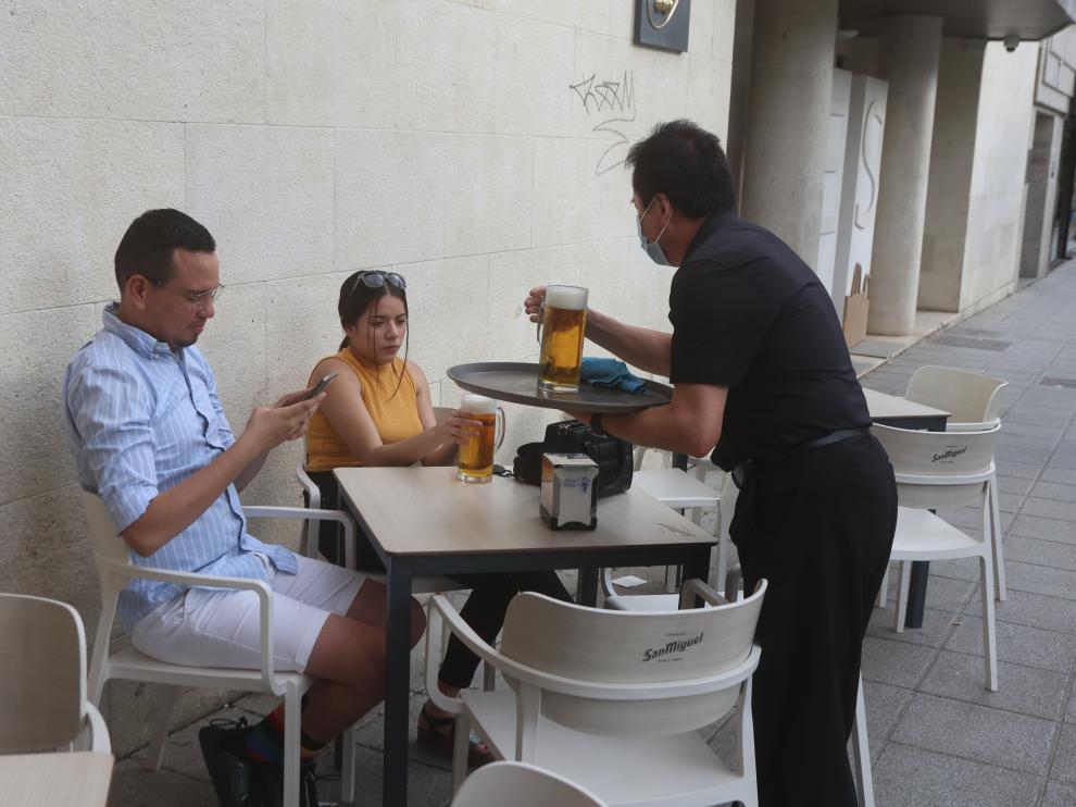 Un camarero sirve a unos clientes en una terraza del centro de la capital oscense.