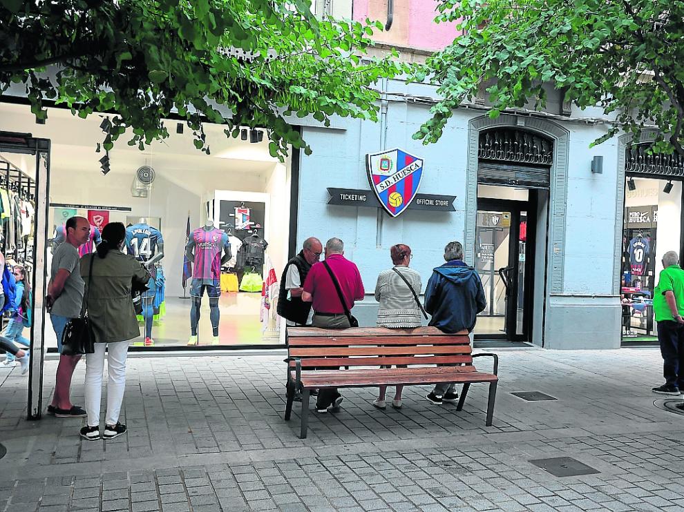 Varios socios esperan en la puerta el momento de la apertura matinal de la tienda del club.