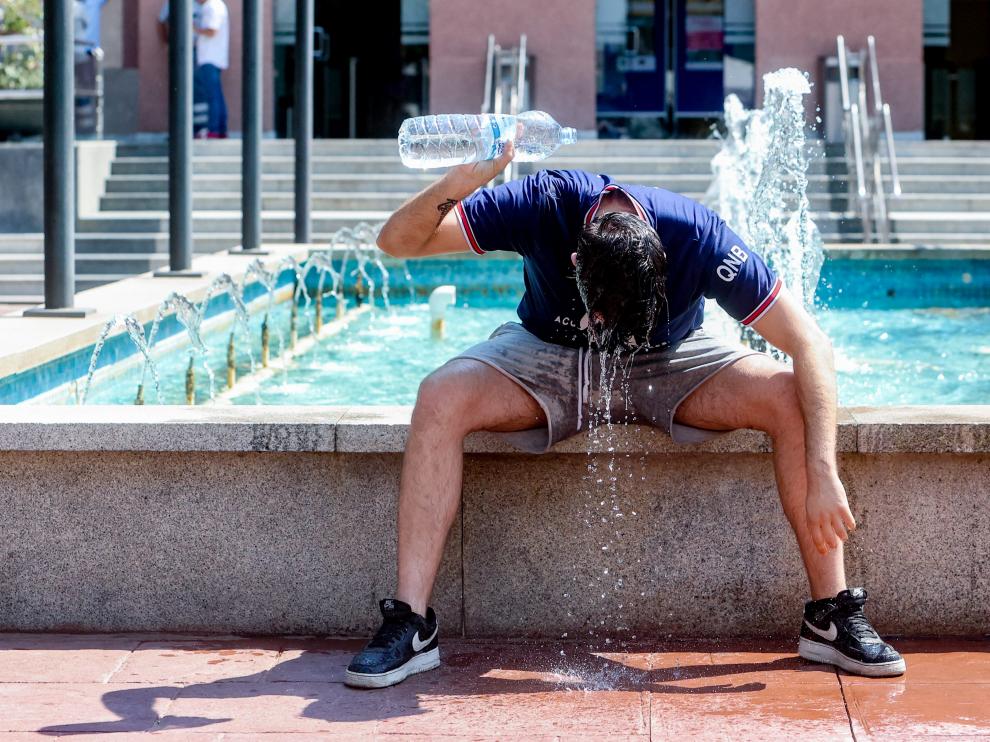 Un joven se tira una botella de agua por encima para combatir la segunda ola de calor del verano. F