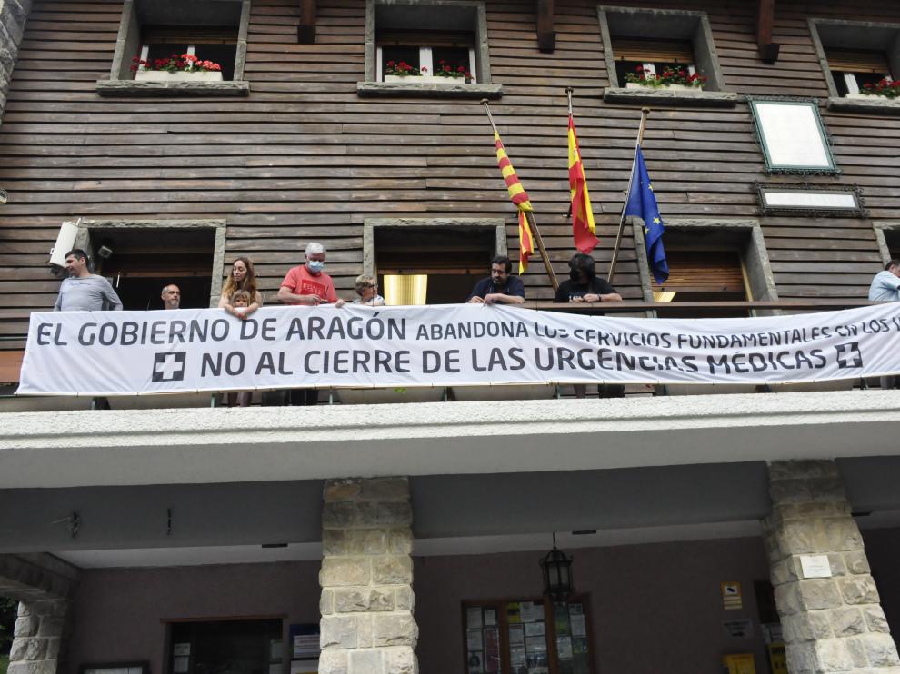 Vecinos de la zona colocando la pancarta contra el cierre de las urgencias médicas en el balcón del Ayuntamiento de Canfranc.